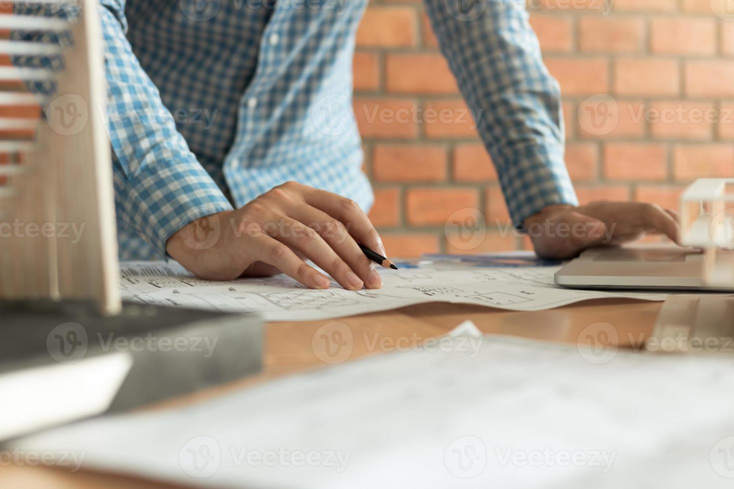 Close up hand engineering man standing examining working on blueprint. photo