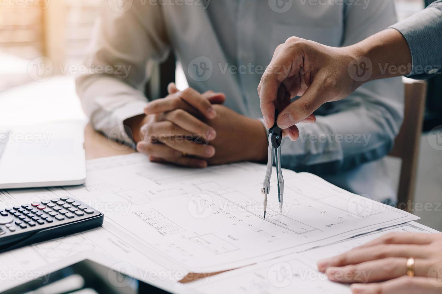 Two engineering working together and using digital tablet looking blueprint and analysis with architectural plan on desk. photo