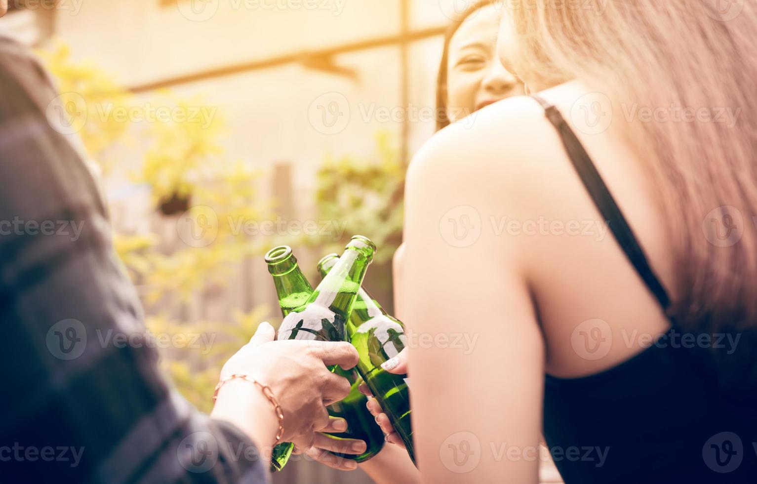 Asian group enjoying toasting drinks party with holding beer bottle clinking. photo