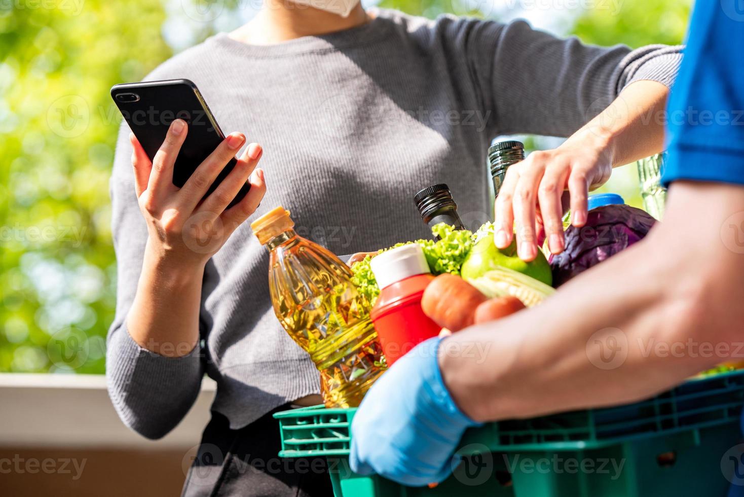 Woman customer checking groceries that ordered online and delivered by deliveryman at home, food delivery service in the time of pandemic concept photo