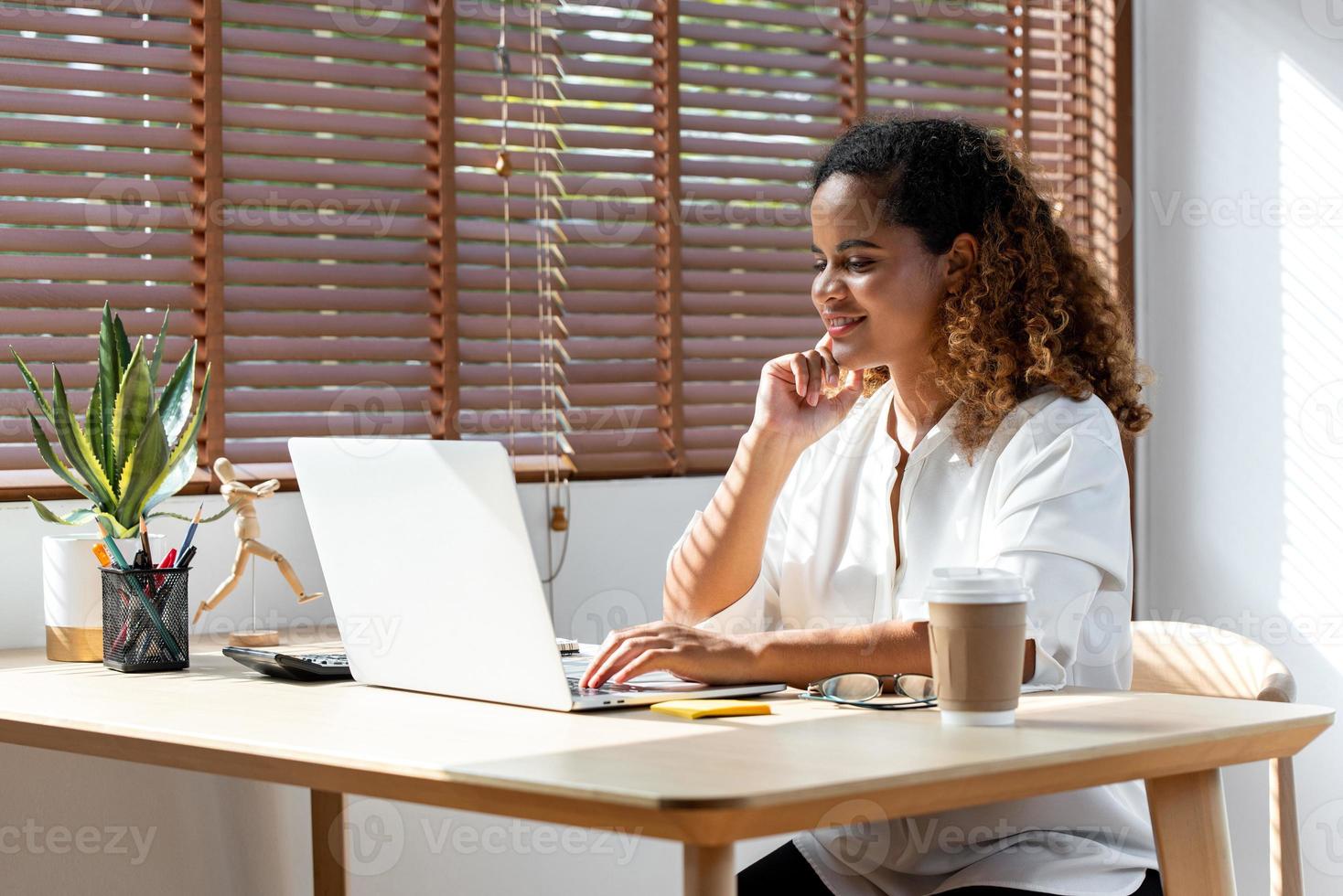 Young happy African-American woman using laptop computer working from home in the time of pandemic photo
