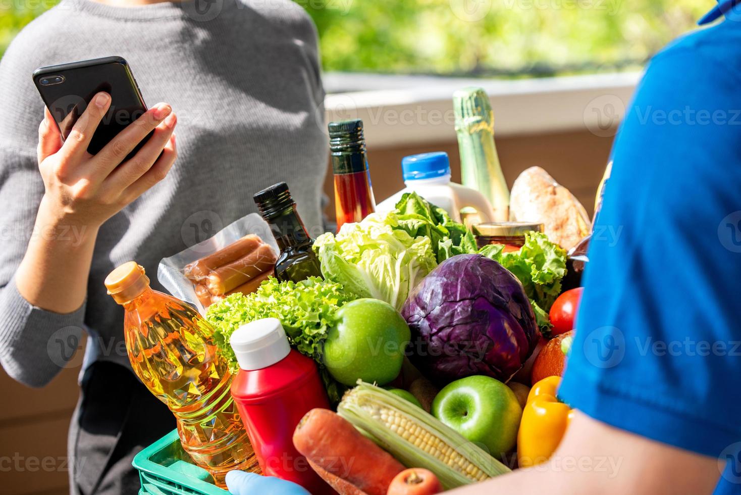 Delivery man delivering groceries that ordered online to a woman customer at home, food delivery service in the time of pandemic concept photo