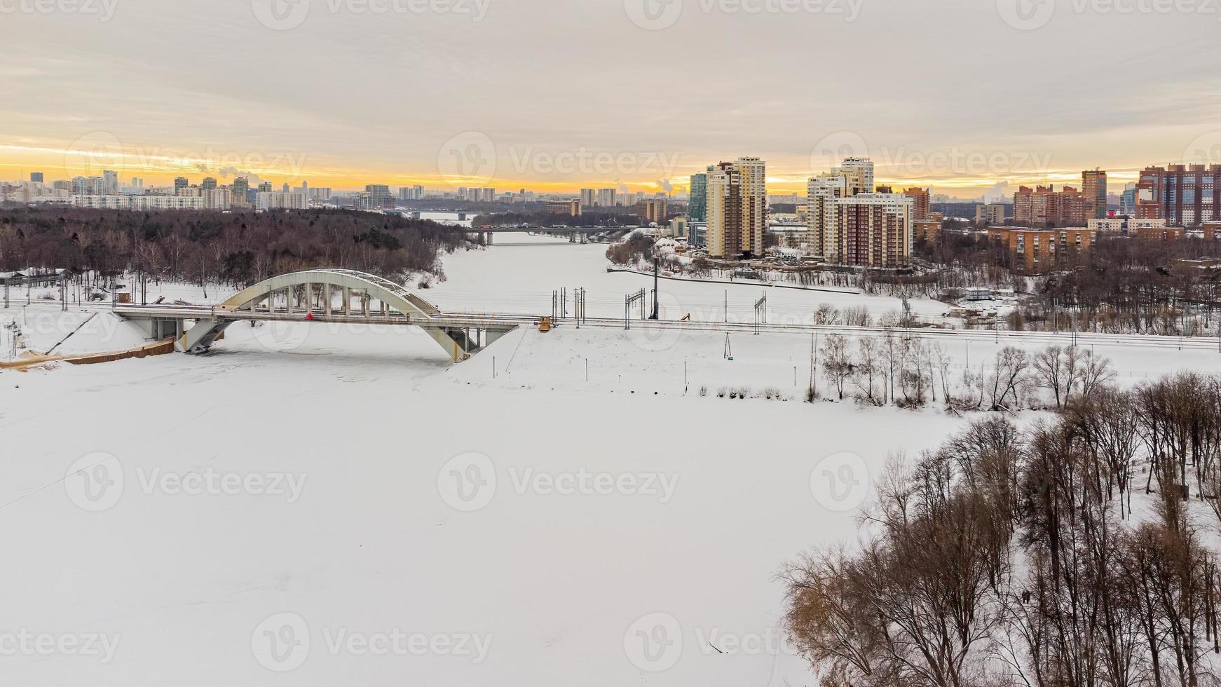 A bird's-eye view of the icy river with a bridge at sunset. photo