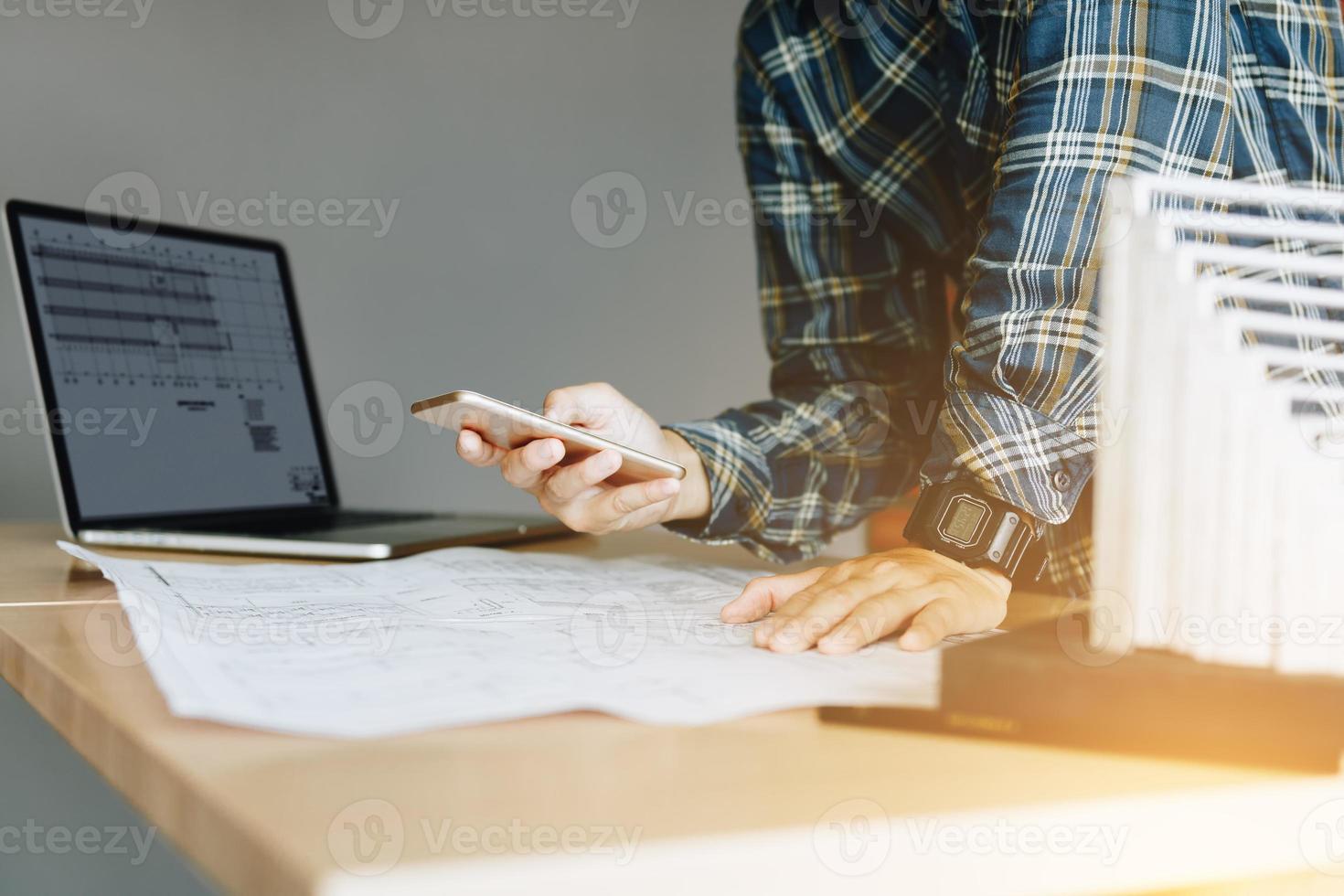 Engineering man standing and message to customer on smartphone and working in modern office. photo