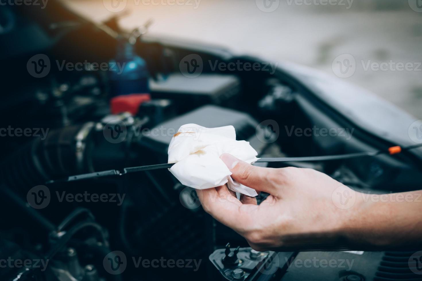 Car mechanic is checking the engine oil of the car using a steel and cleaner by tissue. photo