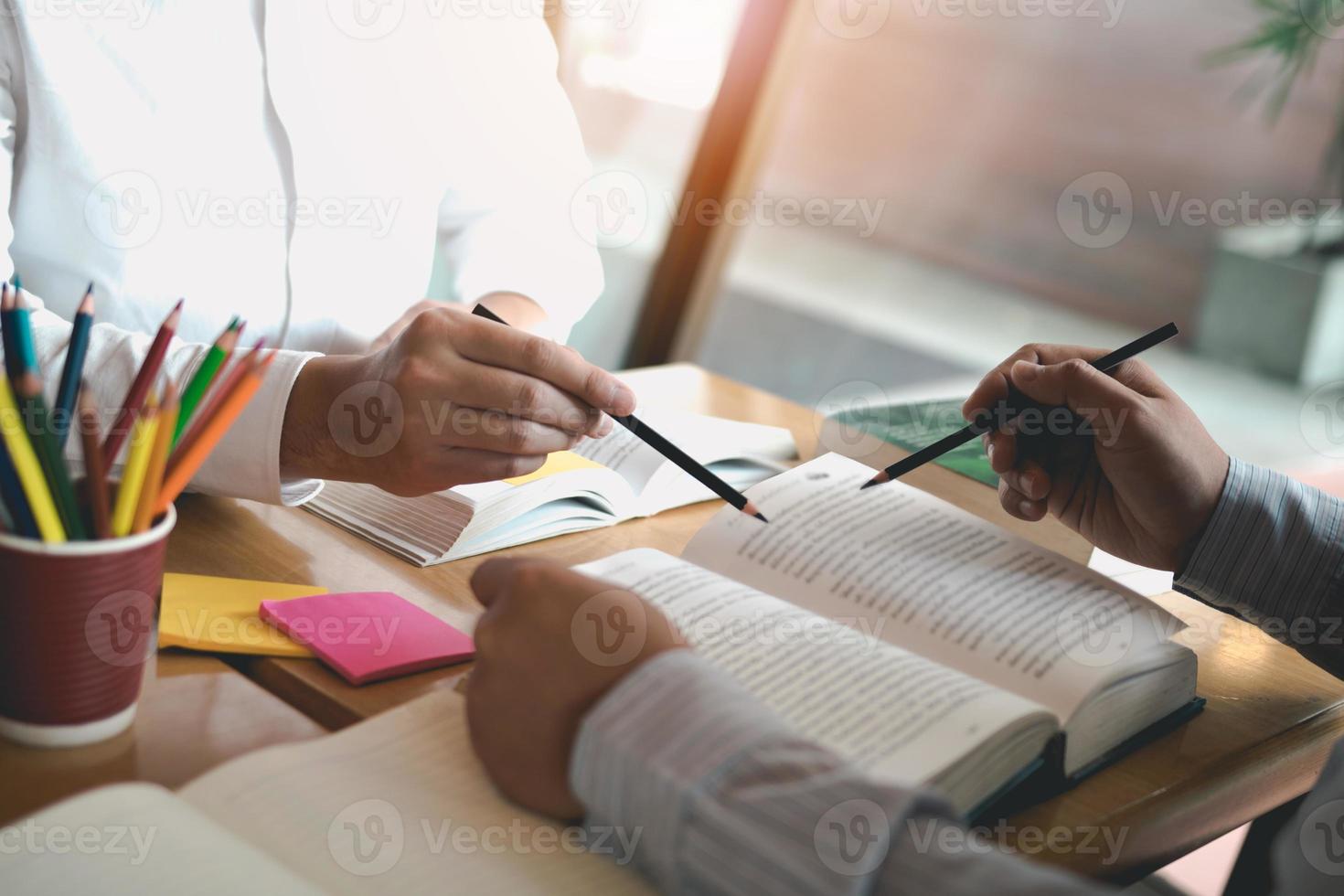 Asian young university students studying together sitting at desk in library. photo