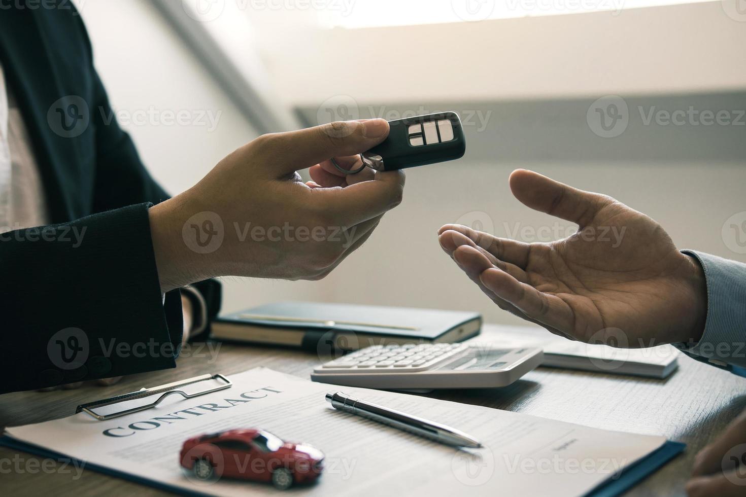 The car salesman is presenting the new car keys to the car buyer at the showroom after signing the contract. photo