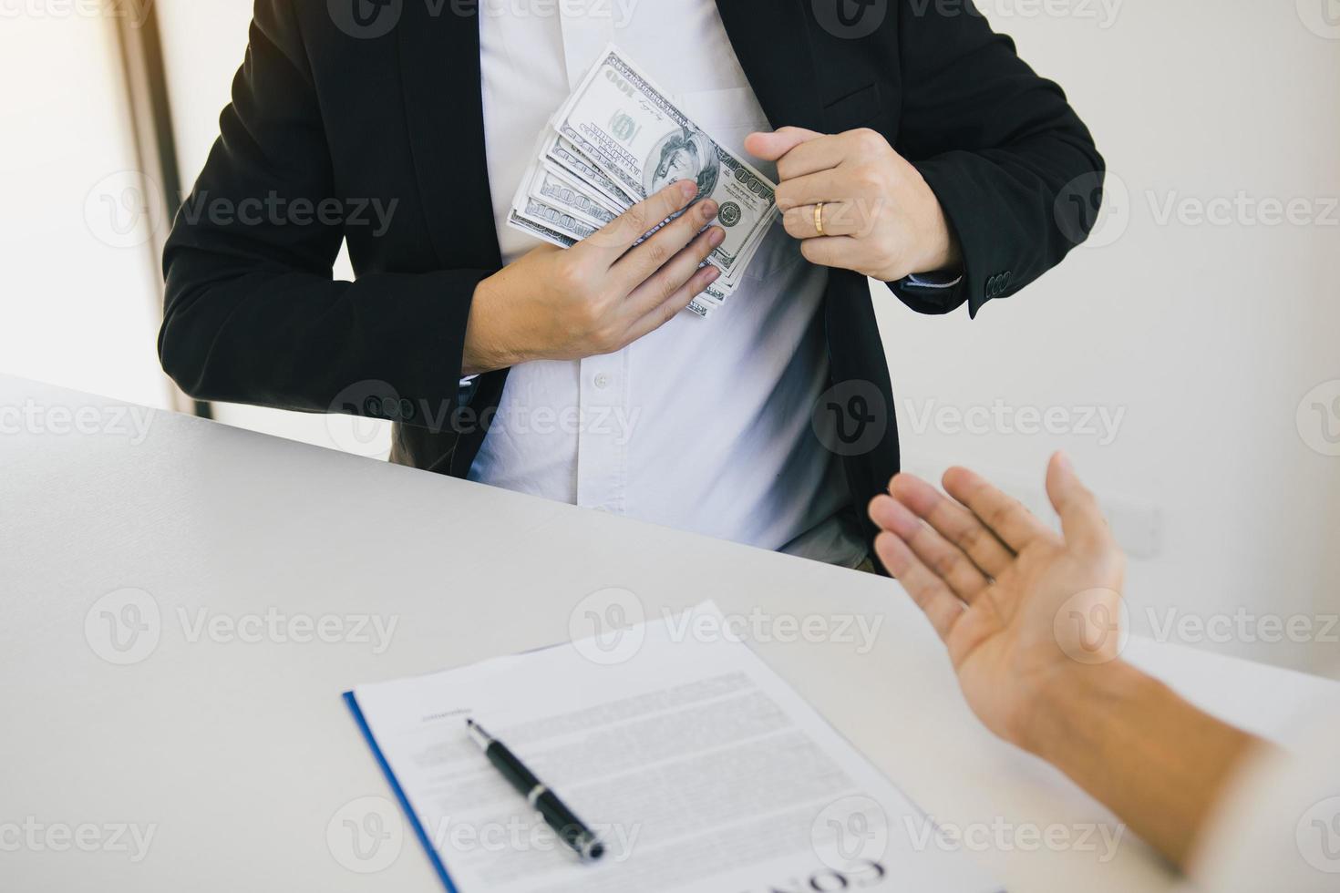 Businessman putting stack of money bills in his suit coat pocket. photo