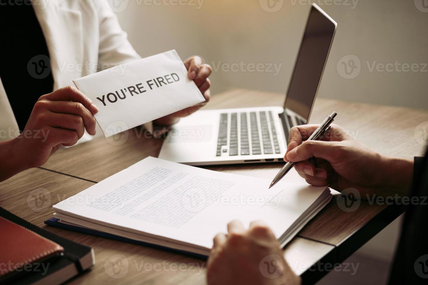 Female manager handed out the dismissal certificate to the male employee while signing the contract to quit from or resign. photo
