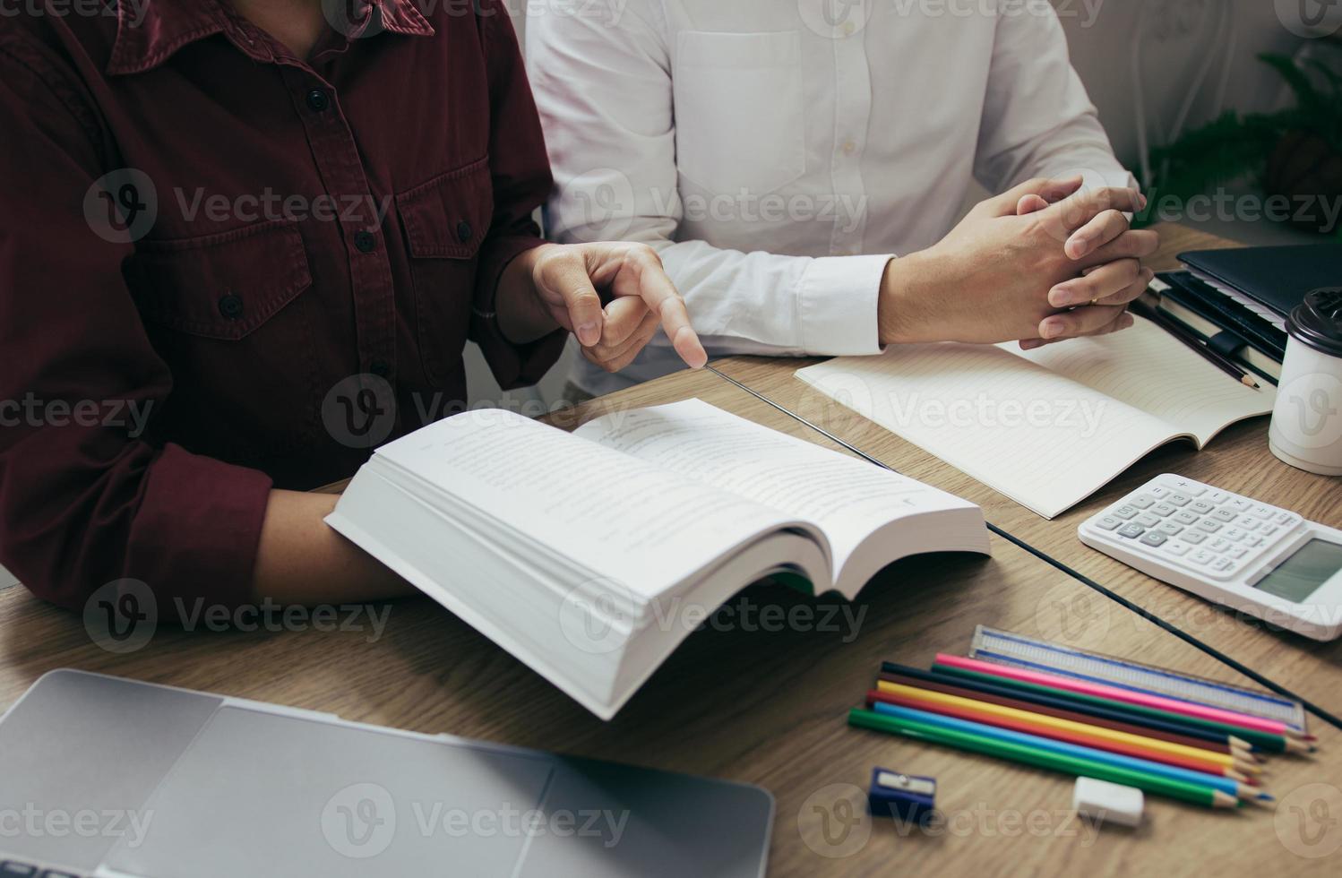 Asian young university students studying together sitting at desk in library. photo