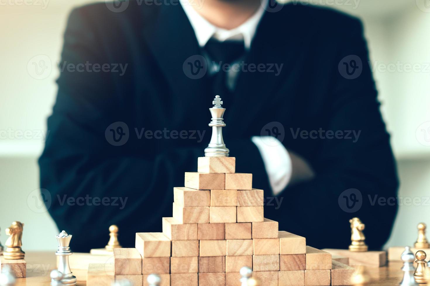 concepto de liderazgo con un hombre de negocios mirando ajedrez en un bloque de madera superior. foto