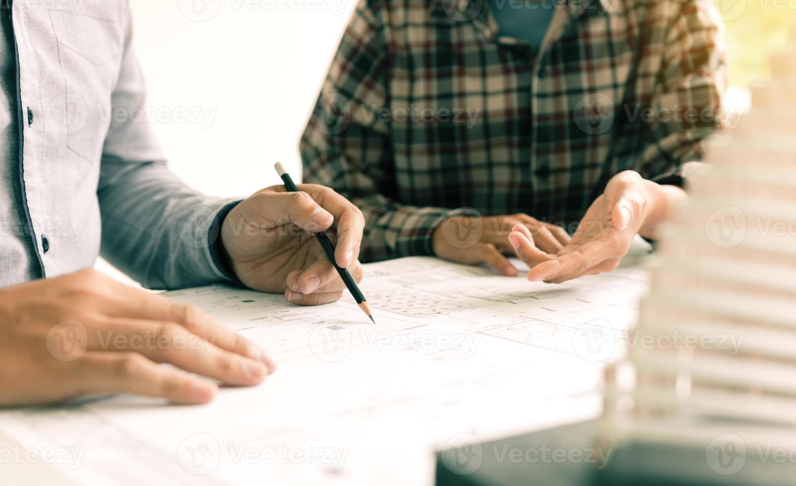 Two architect people sitting and presents plan on blueprints. photo