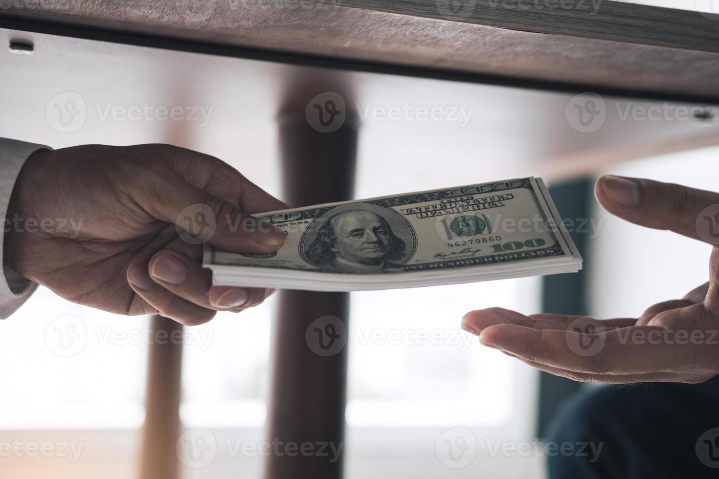 los empresarios están recibiendo dinero debajo del escritorio que es un soborno de sus socios con los cuales ambos son corruptos en la sala de la empresa. foto