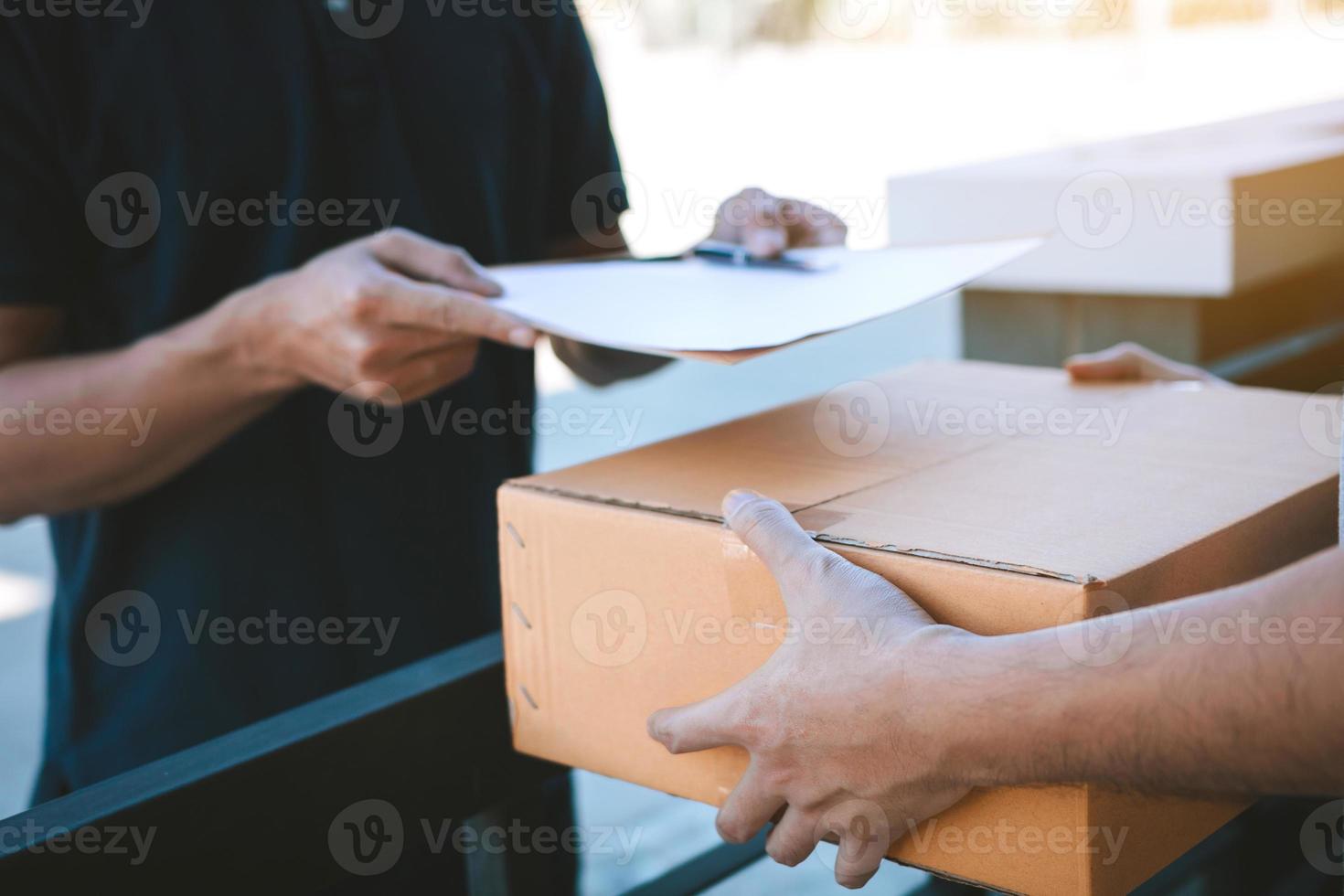 Young staff delivery man of the parcel carrier is submitting the documents to the customers to receive at home. photo