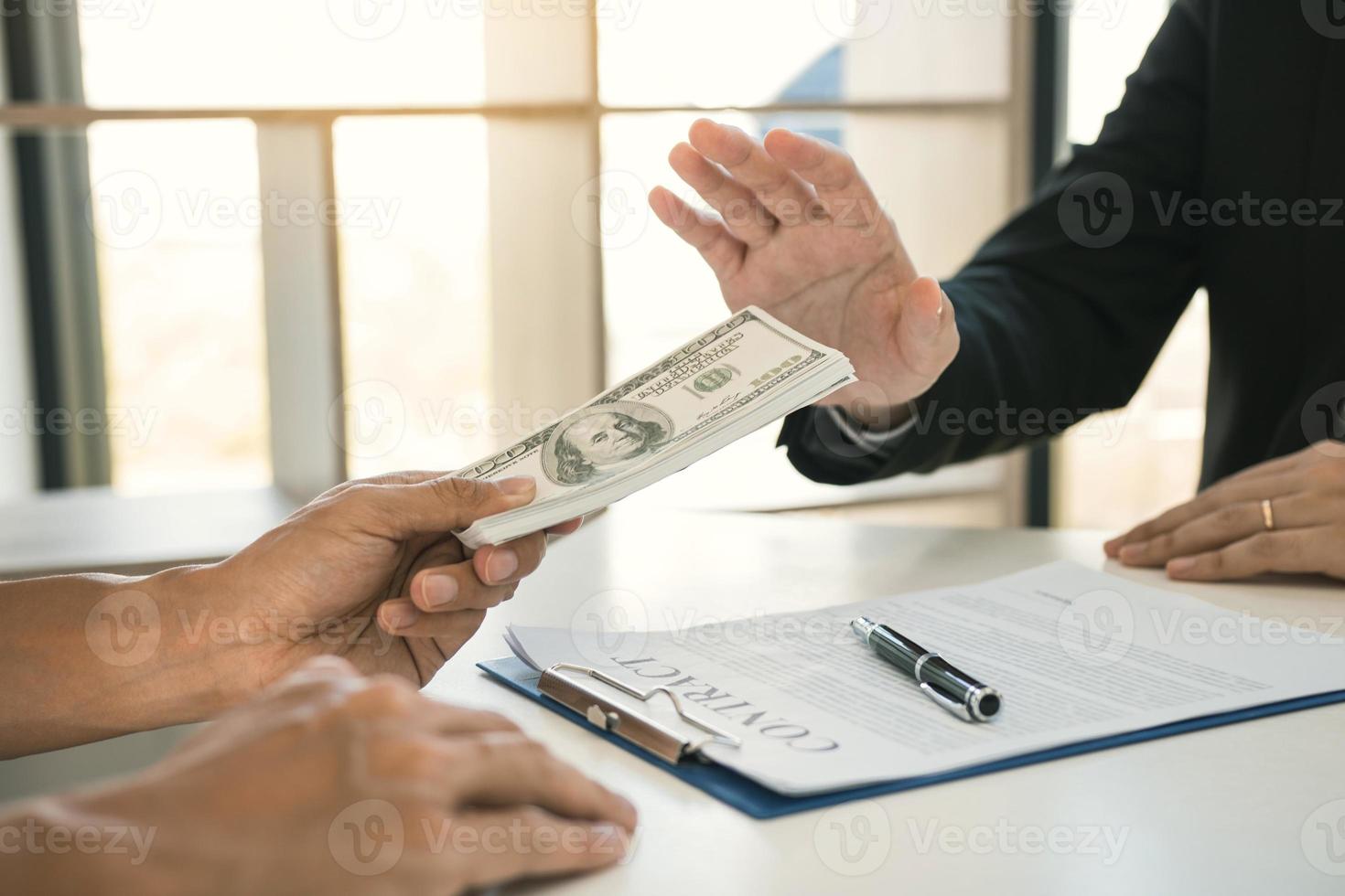 Business person refusing bribe given money by partner with anti bribery corruption concept. photo