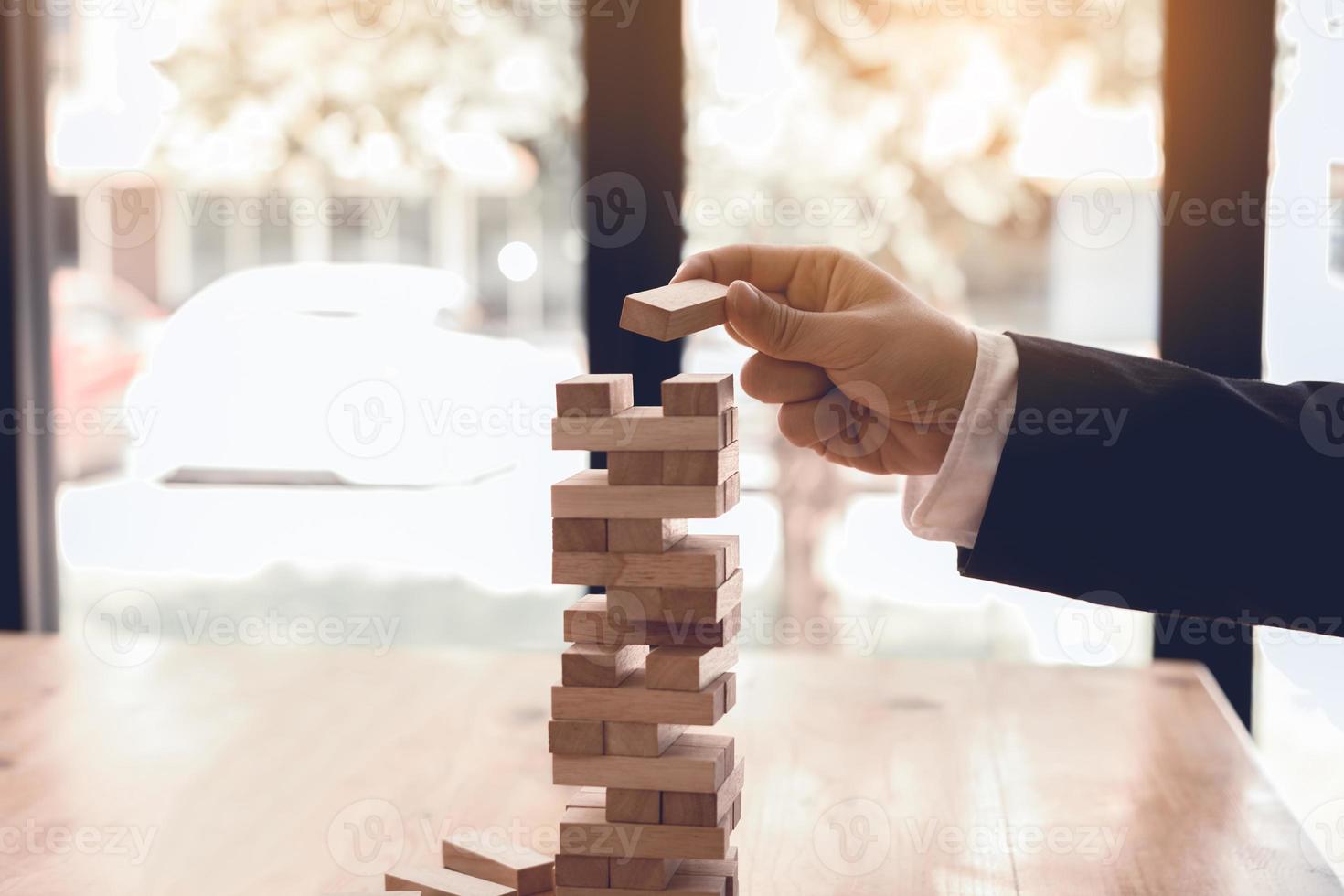 Hand of businessman playing wood blocks stacks game with planning strategy of project management. photo