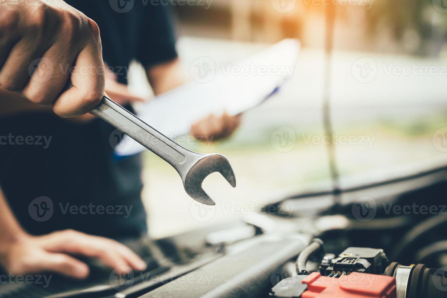 Car mechanic is holding a wrench ready to check the engine and maintenance. photo