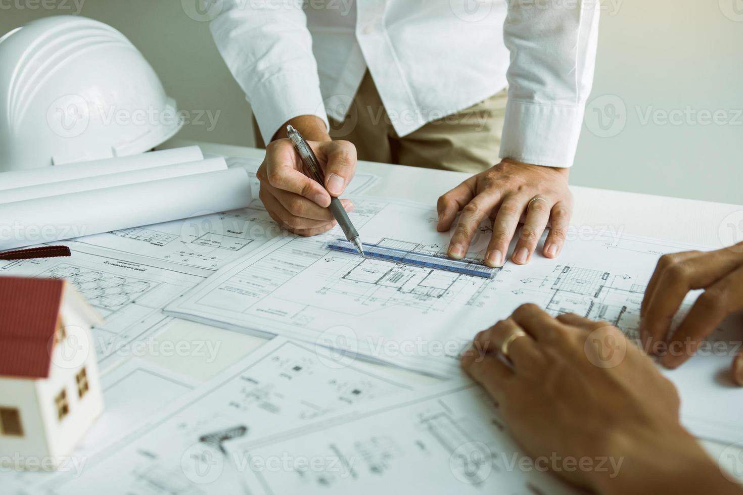 Architects engineer working with blueprints on table and discussing project together at the meeting in the office. photo