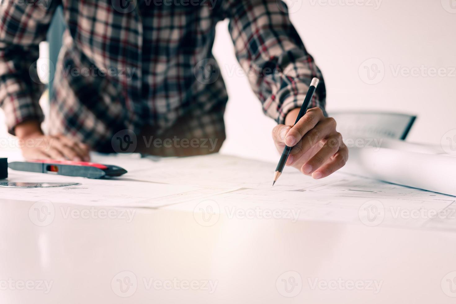 Hand of young engineering man drawing on blueprint at table in office room. photo