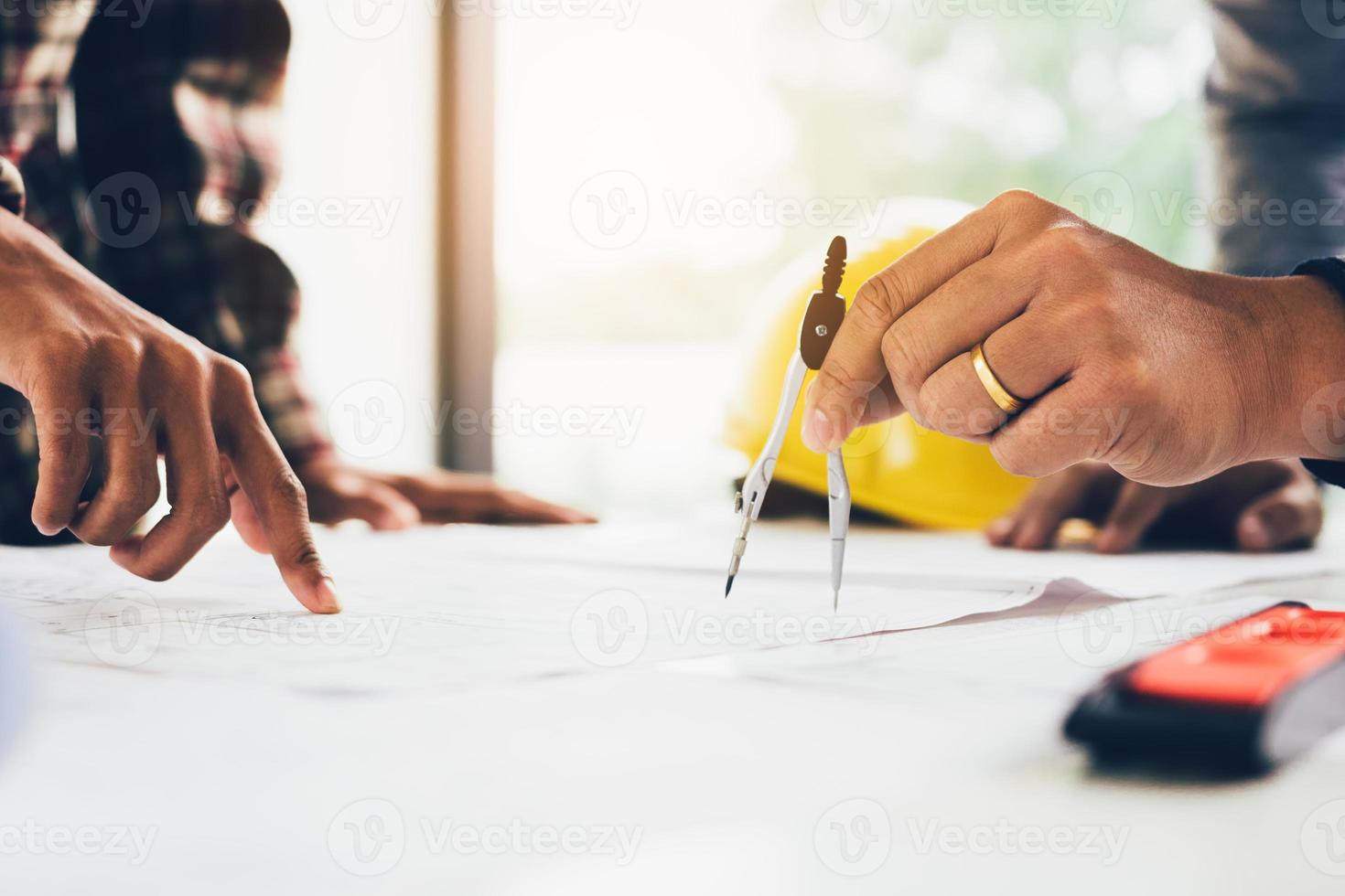 Two architect working at construction site and pointing on blueprint. photo