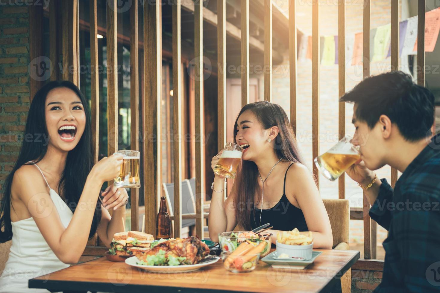 Asian people cheering beer at restaurant happy hour and laughing