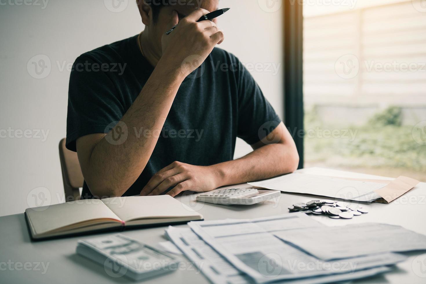 Asian men are stressed about financial problems, with invoices and calculators placed on the table while having stress on problems with home expenses. photo