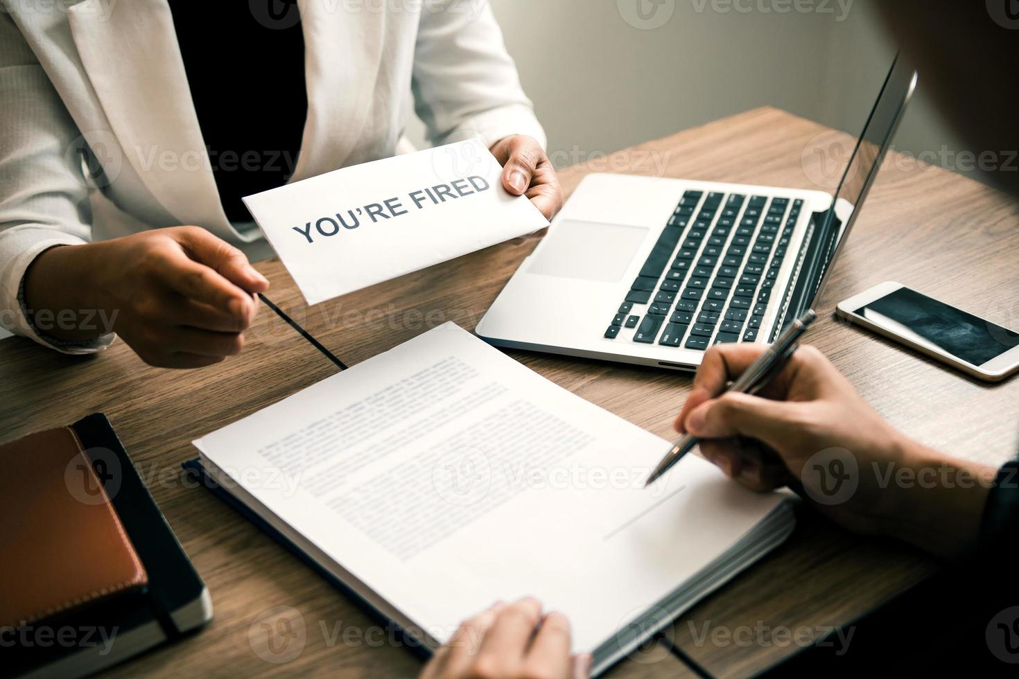 Female manager handed out the dismissal certificate to the male employee while signing the contract to quit from or resign. photo