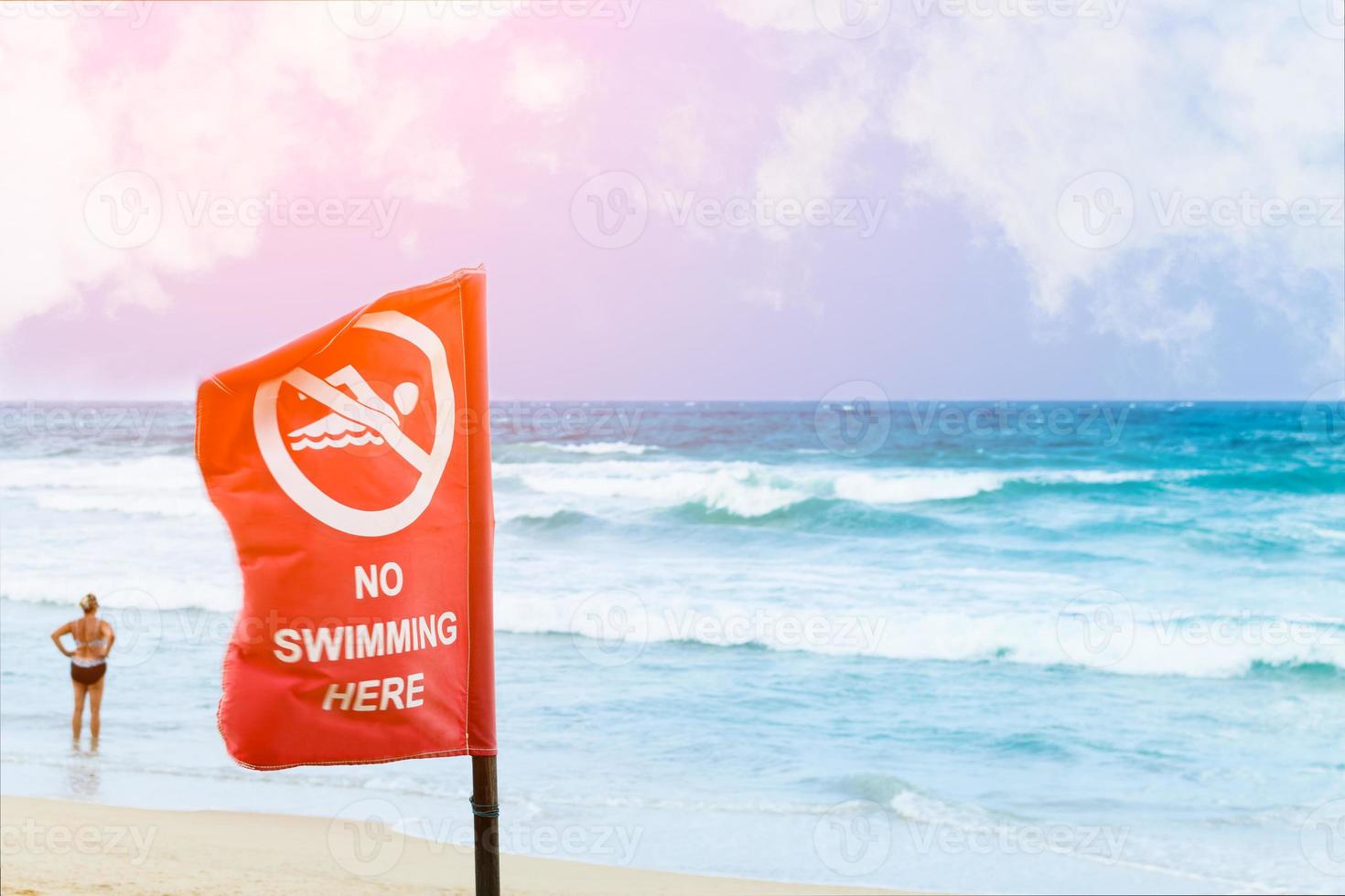 No swimming danger sign at the beach, warning sign at the beach with people swim, caution no swimming allowed. photo