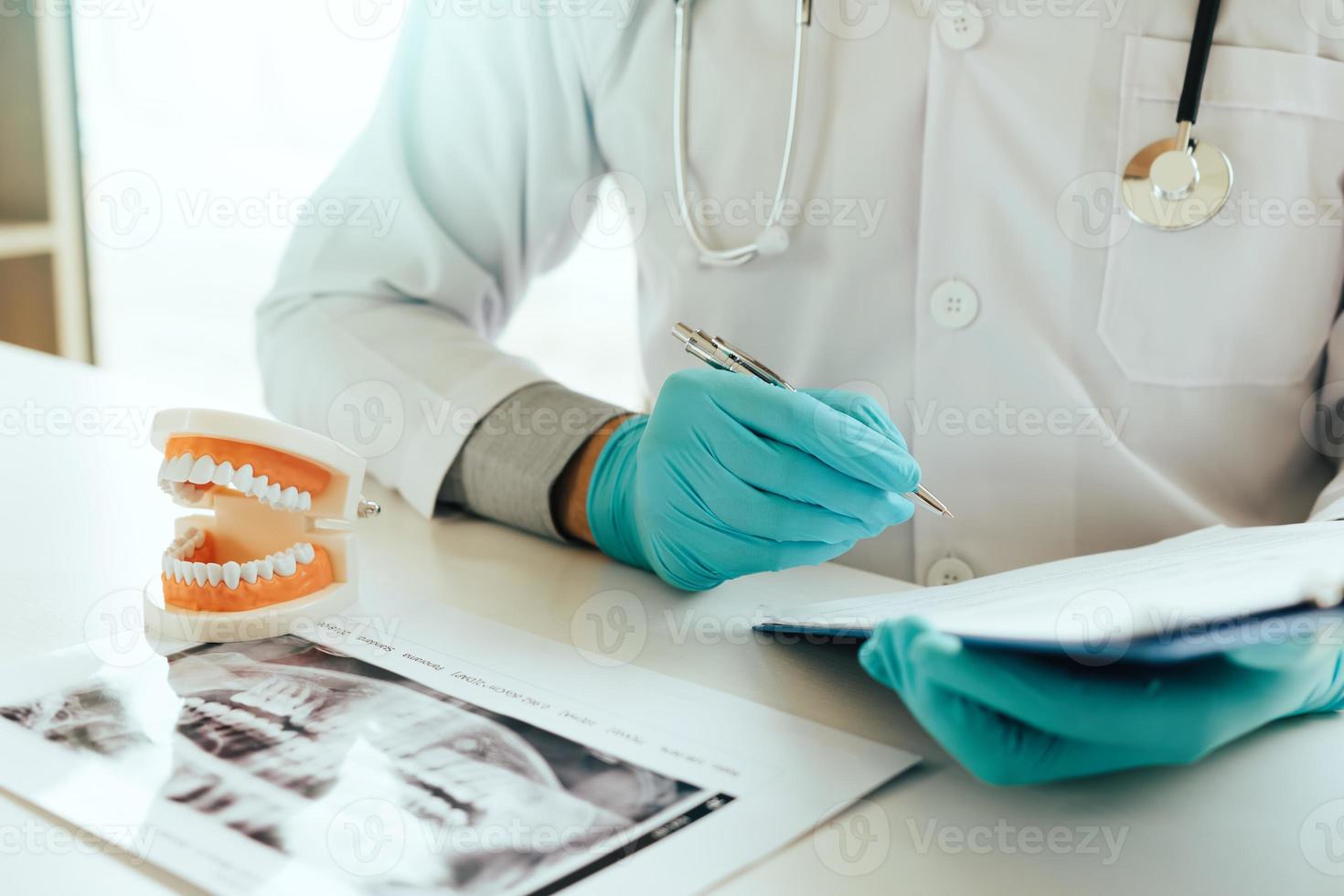Dentist writing analysis and making note report to patient in office. photo