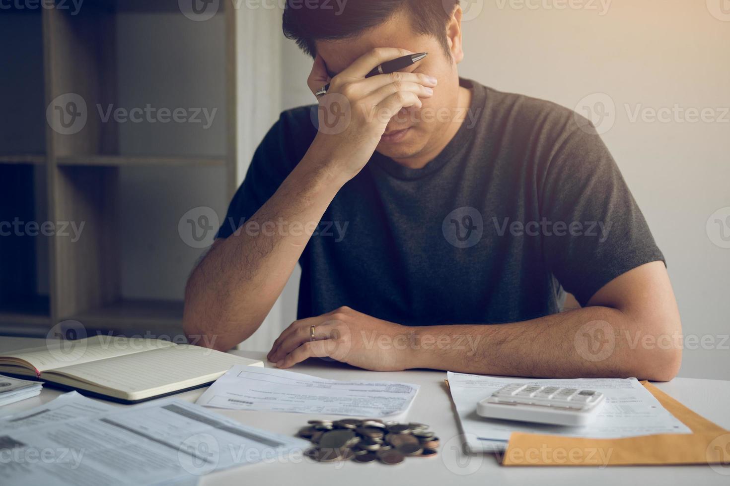 Asian men are stressed about financial problems, with invoices and calculators placed on the table while having stress on problems with home expenses. photo