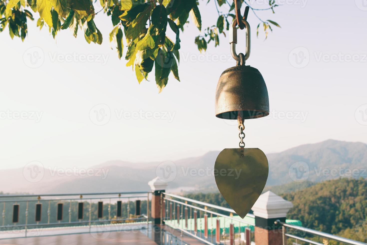 Close up view of golden bell in temple with mountain background. photo