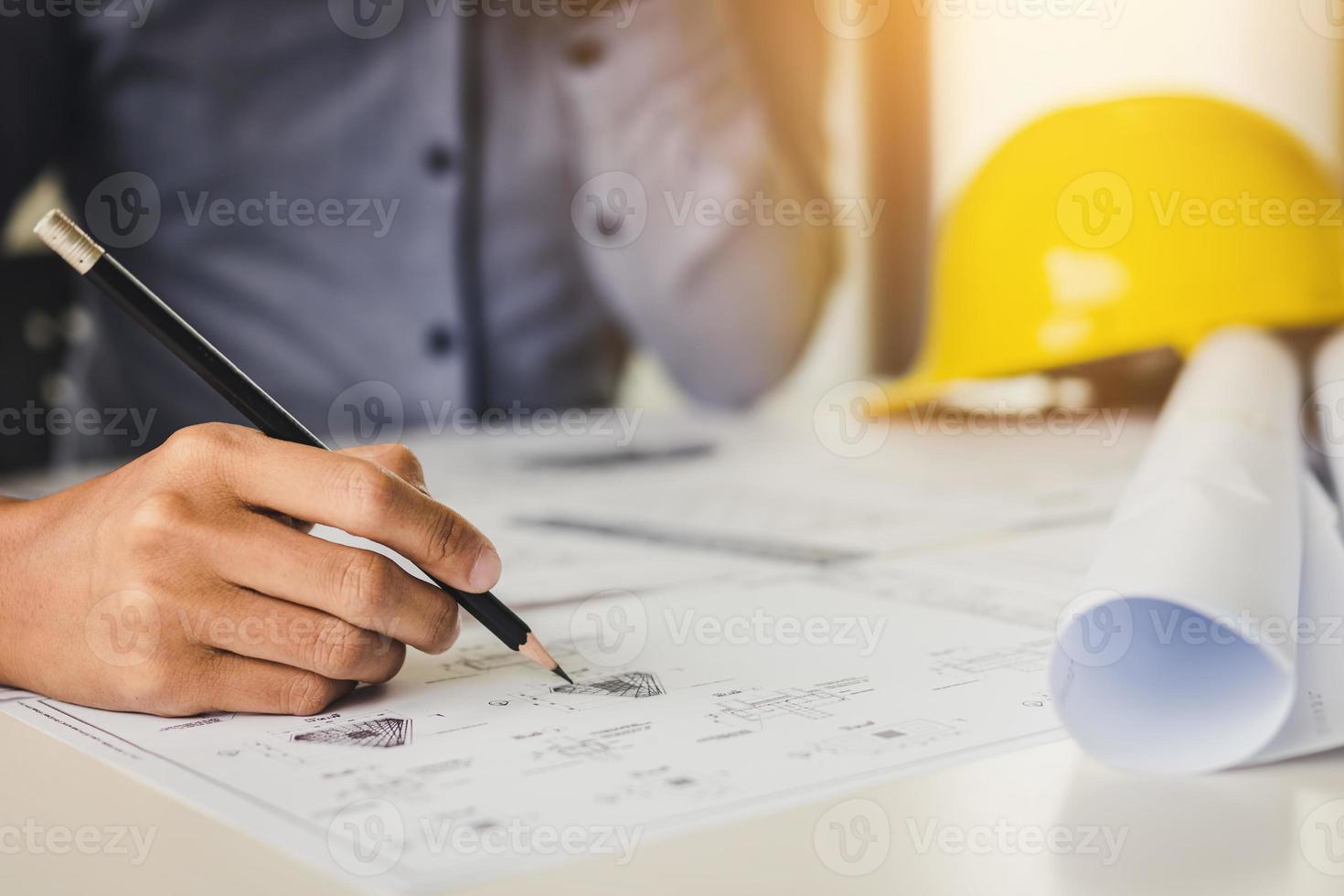 Architect holding pencil and pointing on blueprint. photo