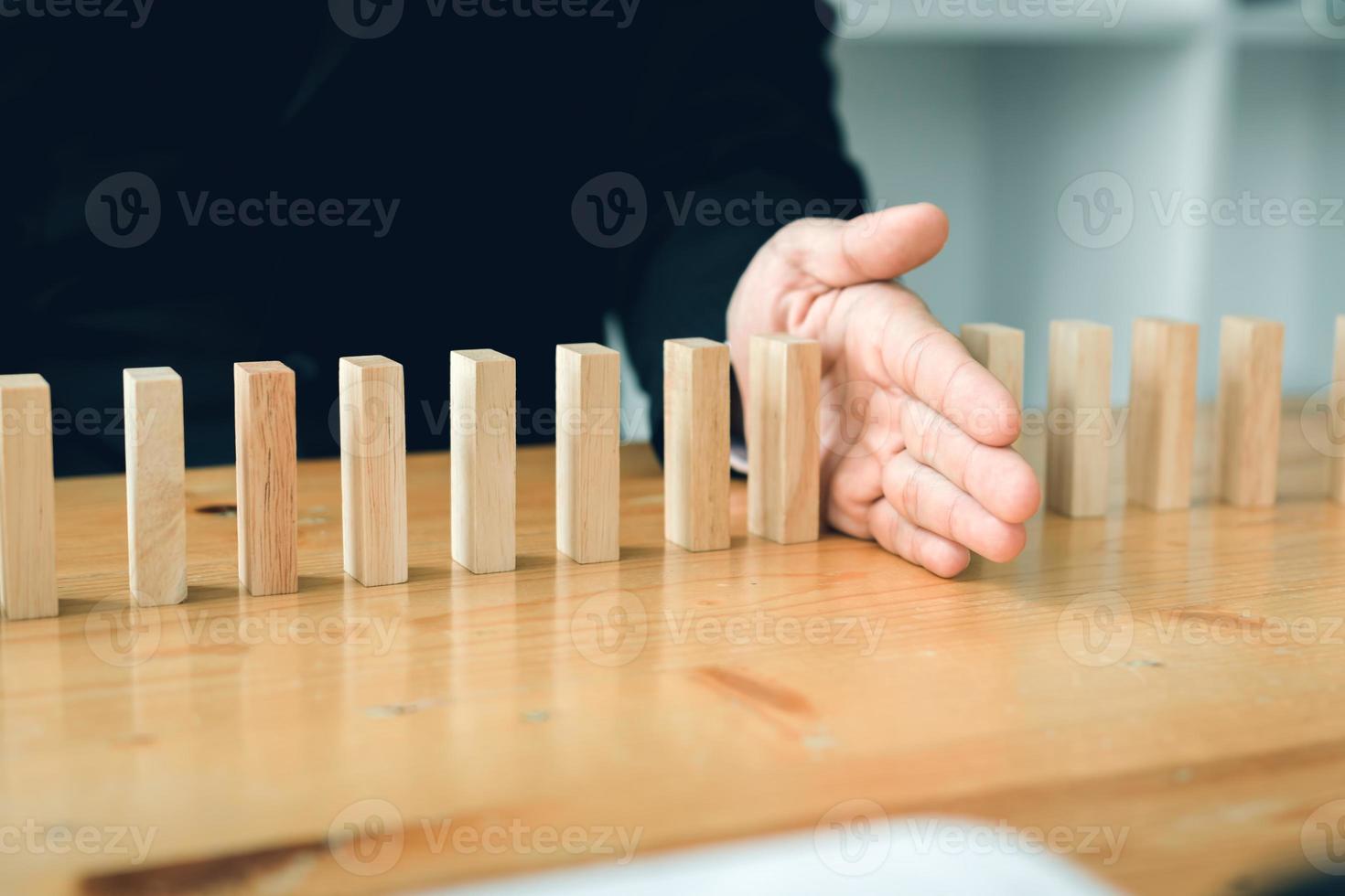 Risk concept with hand of businessman stopping and protection the domino effect. photo