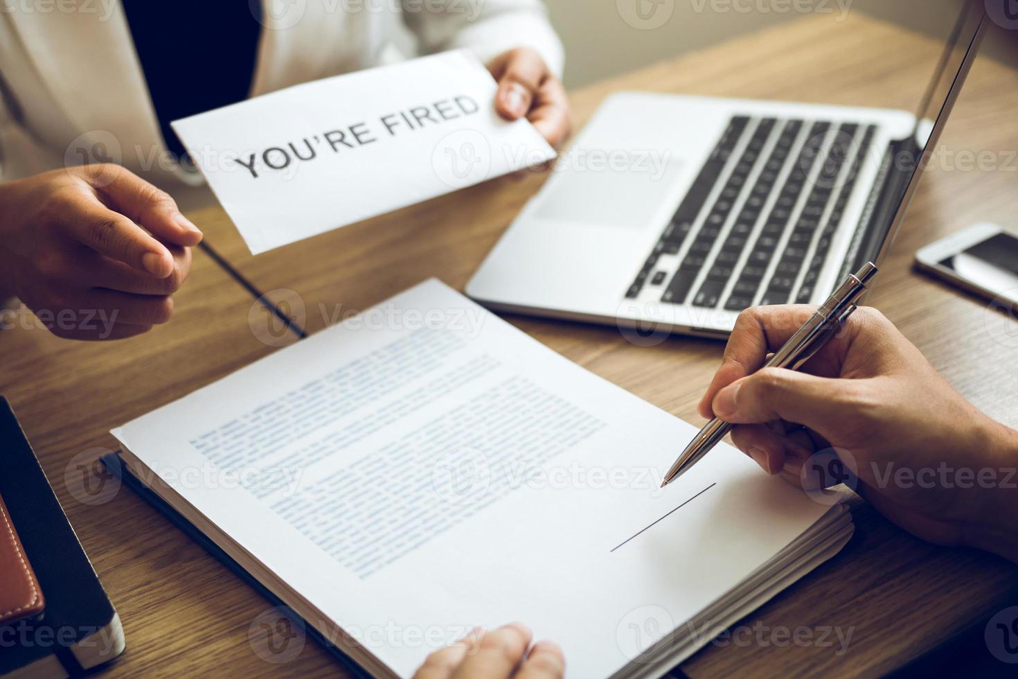 Female manager handed out the dismissal certificate to the male employee while signing the contract to quit from or resign. photo
