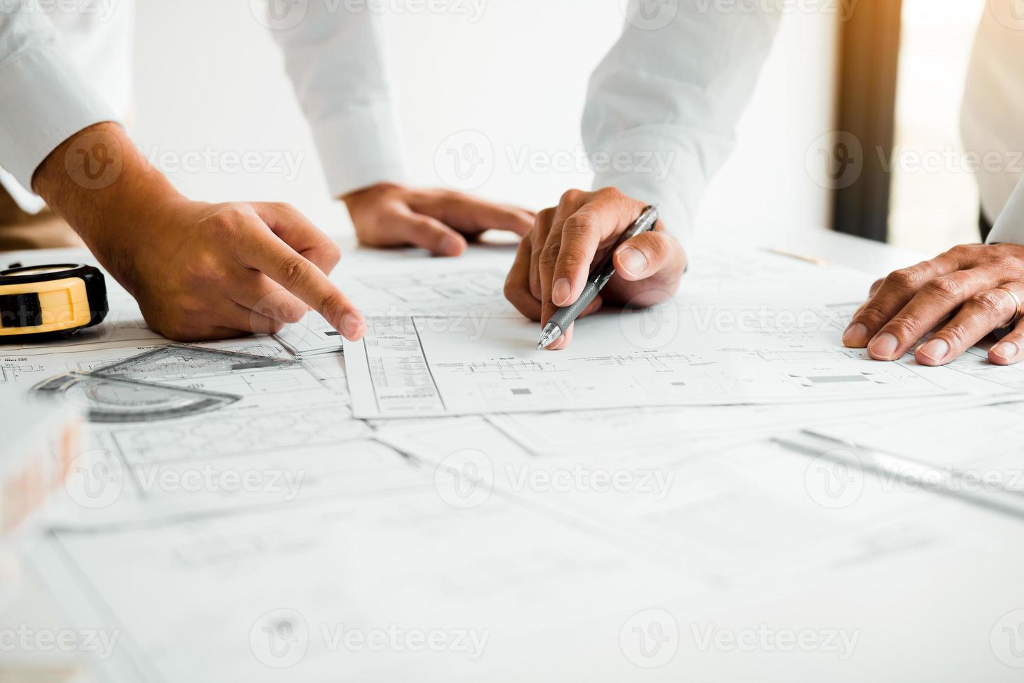 Architects or engineering working with blueprints and discussing project together at the meeting in the office. photo