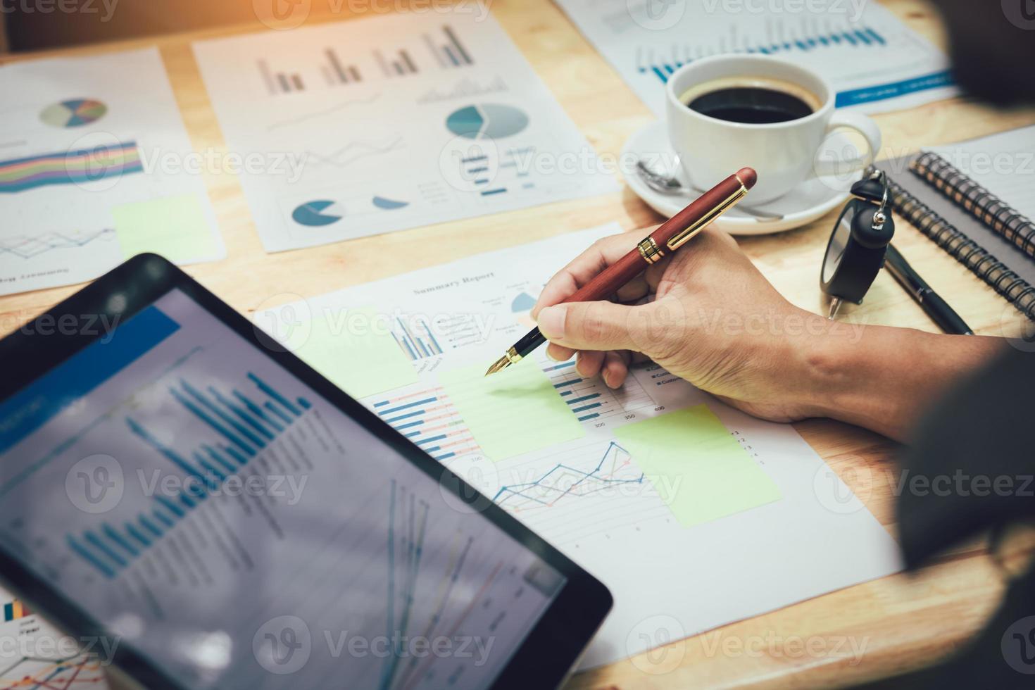 Businessman making note on sticky with looking graph in tablet. photo