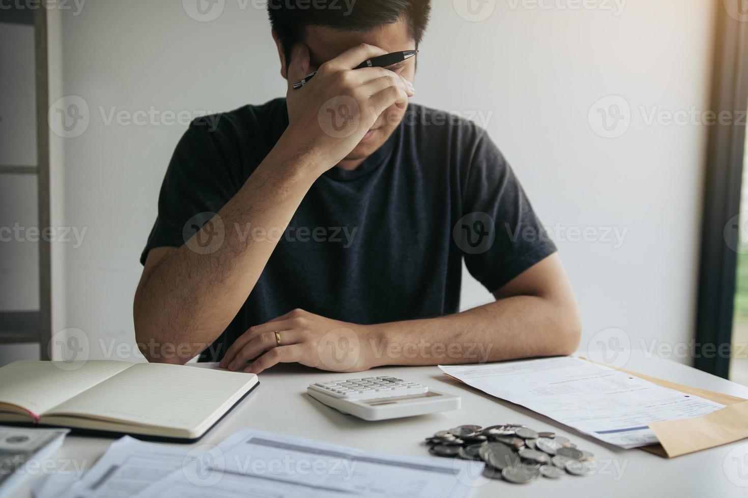 Asian men are stressed about financial problems, with invoices and calculators placed on the table while having stress on problems with home expenses. photo