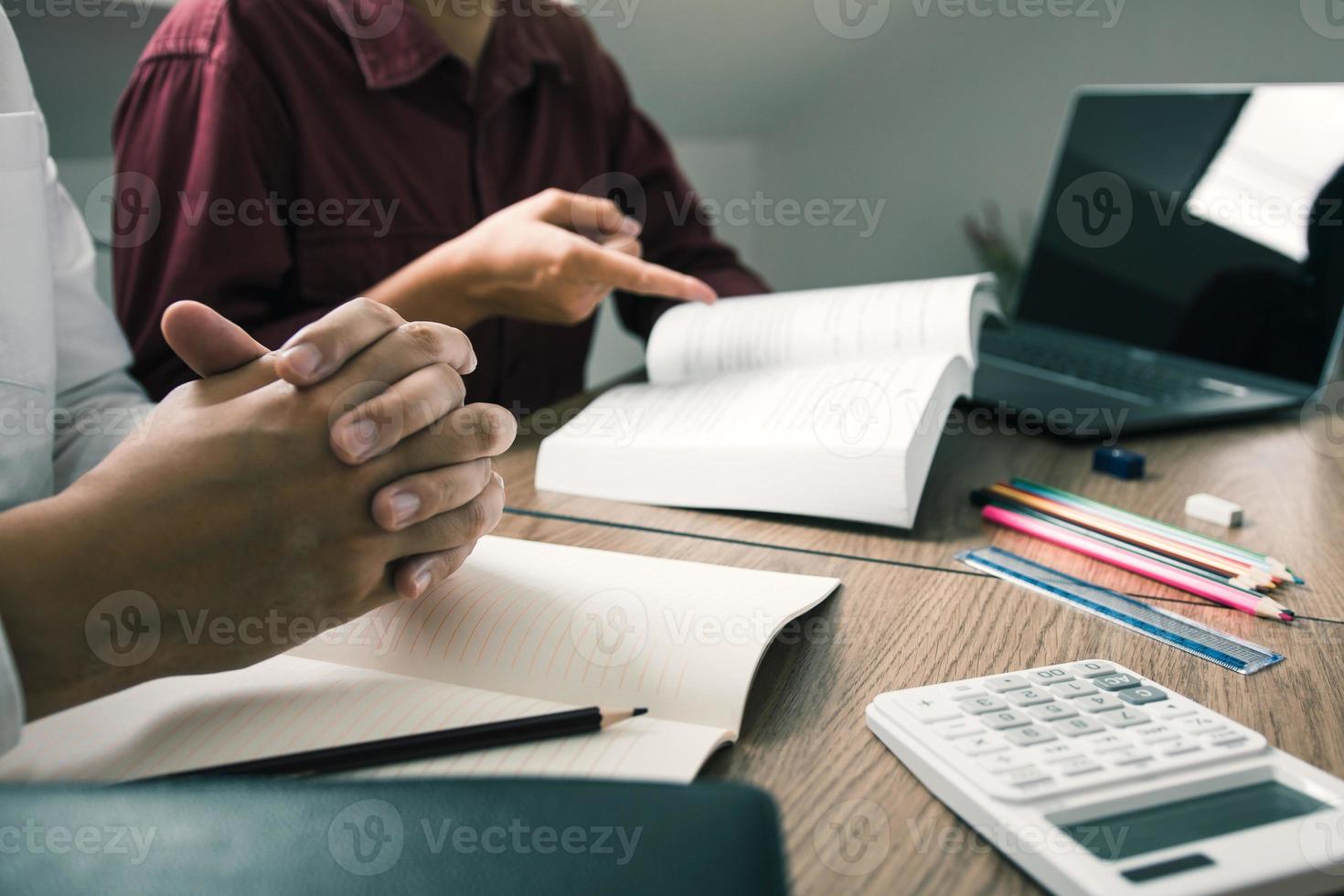 Two student reading textbook for test together in library. photo