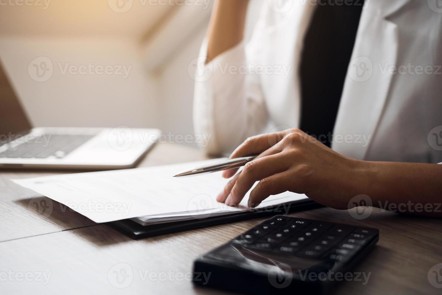 Women are sitting analyzing the company's financial statement plan using a calculator on his desk. photo