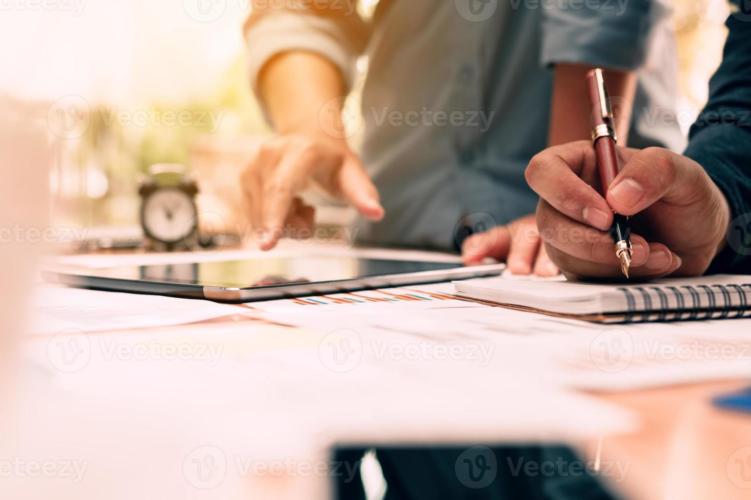 Close up hand man writing make note on notebook and hand pointing with using tablet on desk in office room. photo