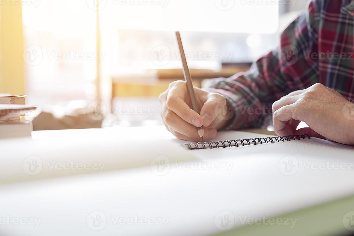 cierre la mano del estudiante escribiendo en papel con un lápiz tomando una prueba. foto