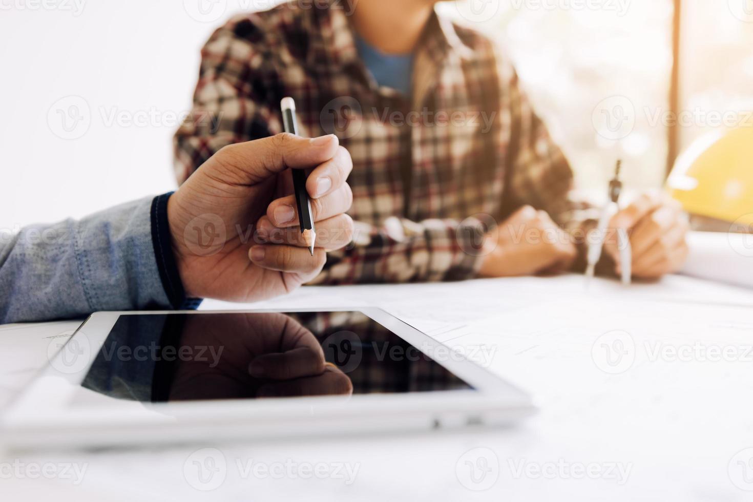 Male engineering using digital tablet with architectural plan on desk. photo