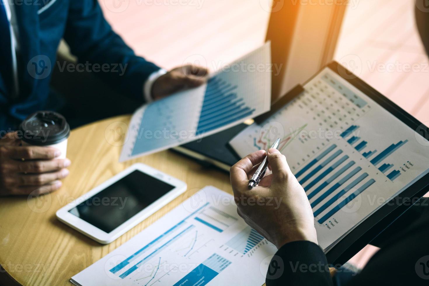 Businessmen pointed out the company performance chart on the table during a strategy discussion and drank coffee in the morning in the office. photo