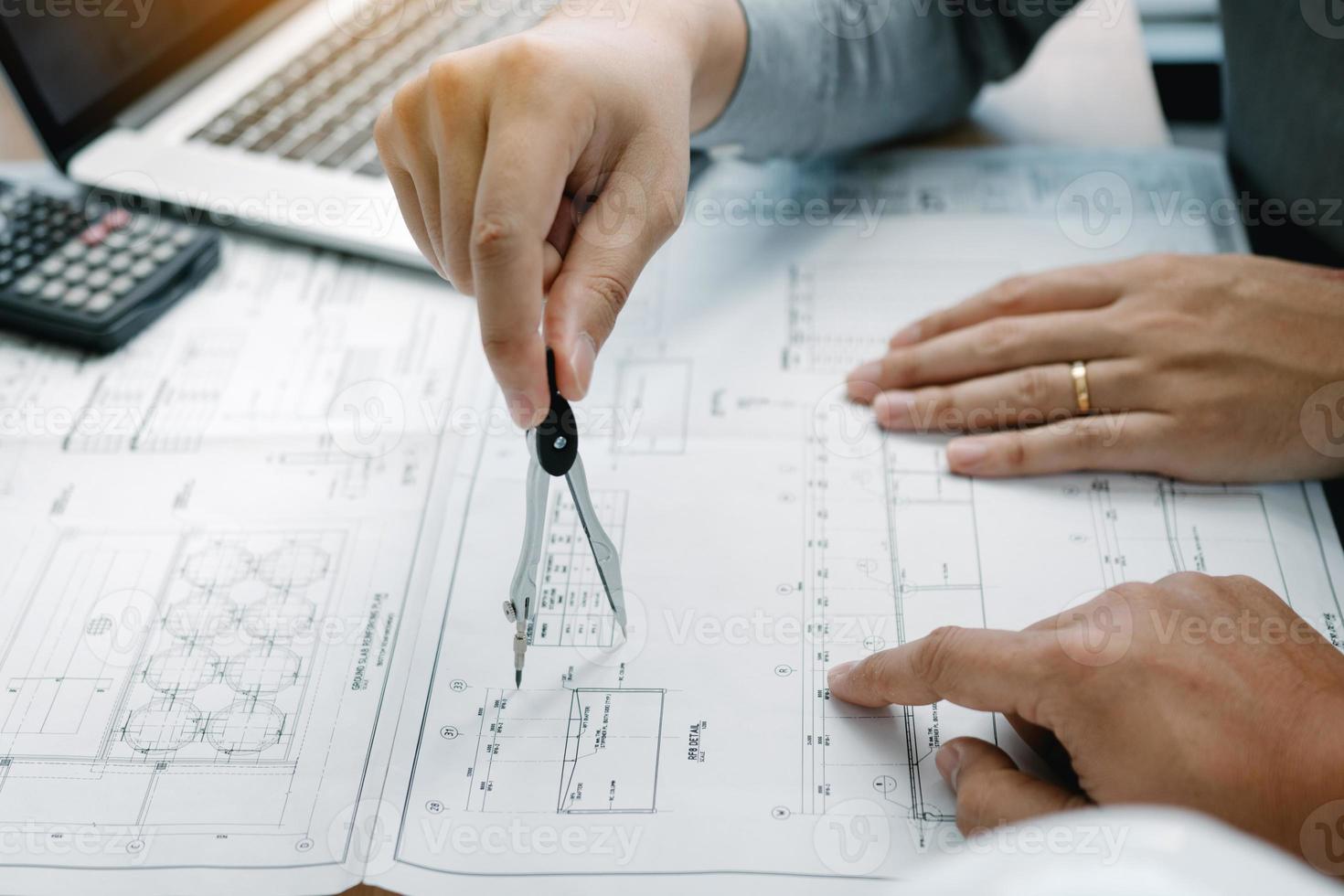 Architect working on blueprint in workplace with partnership and drawing compass. photo