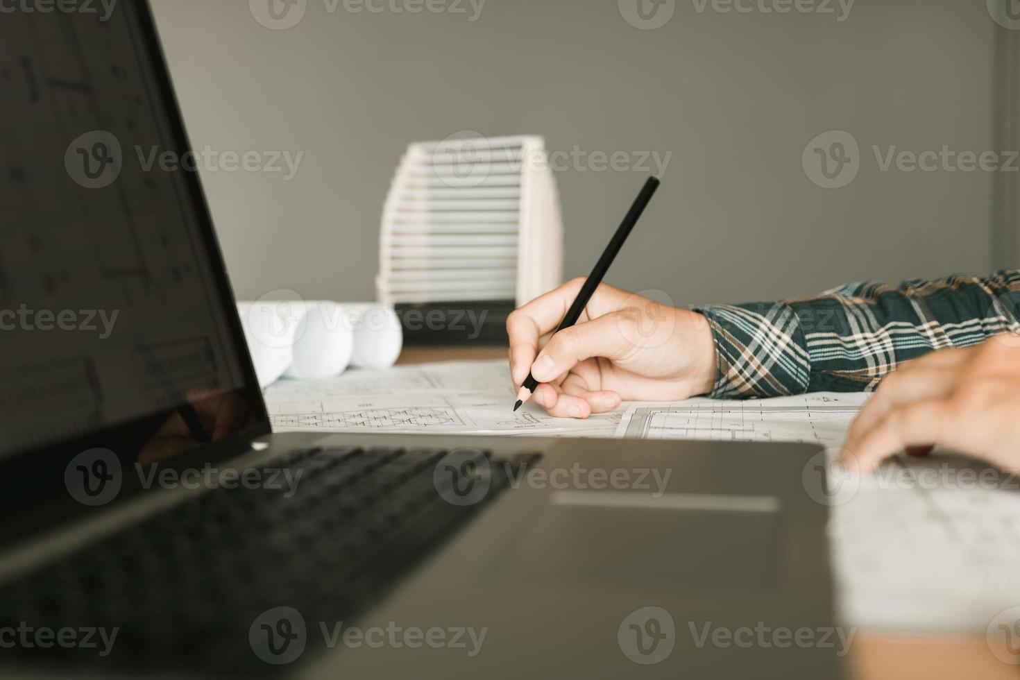 Architect working on blueprint in workplace with laptop and drawing. photo