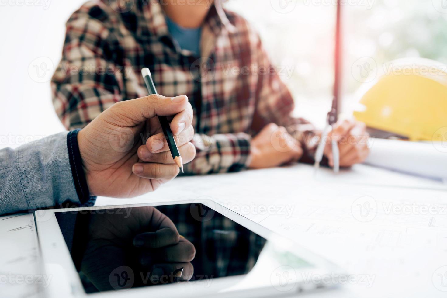 Male engineering using digital tablet with architectural plan on desk. photo