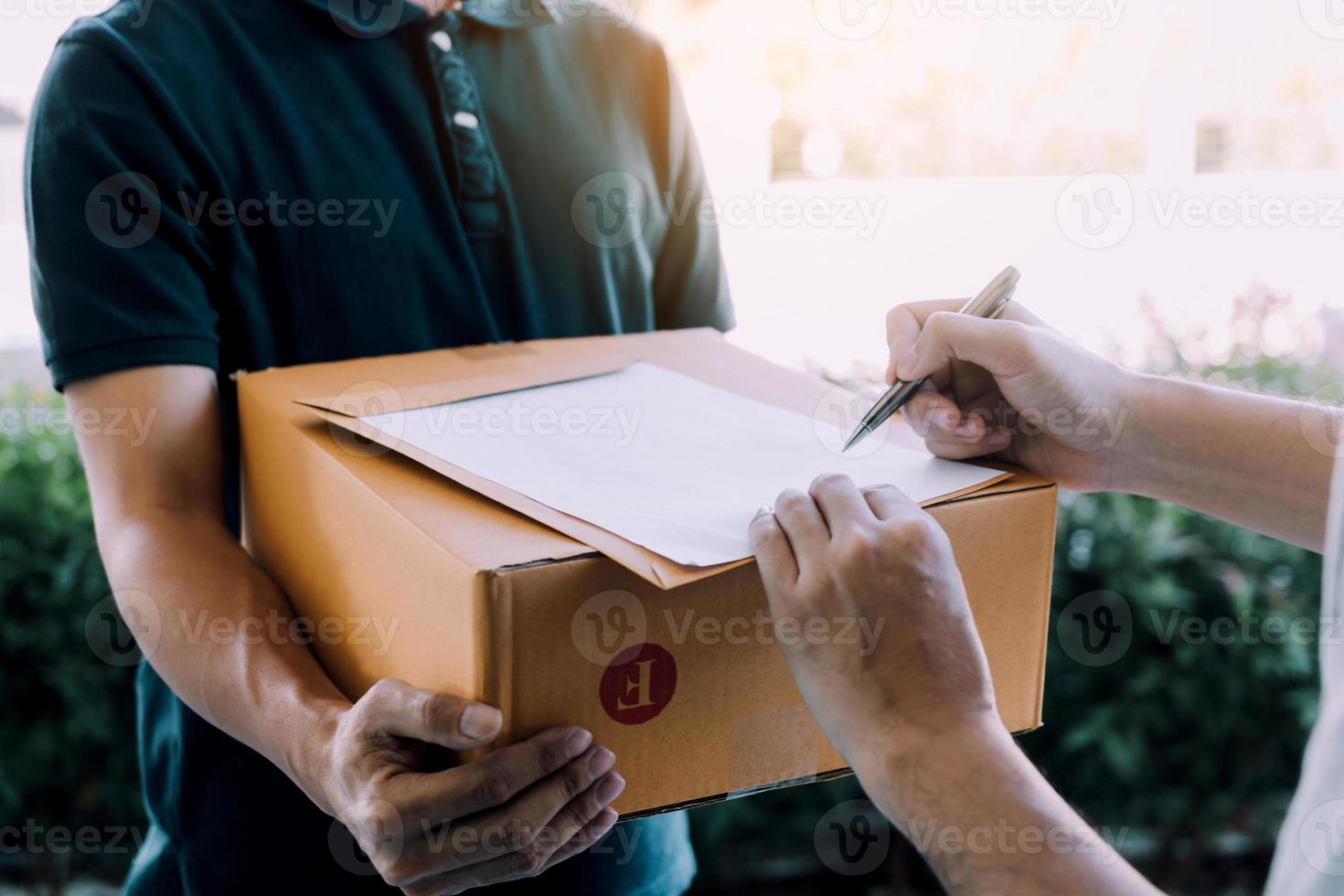 Delivery young man standing at the door of home and carrying parcels for young male to signing. photo