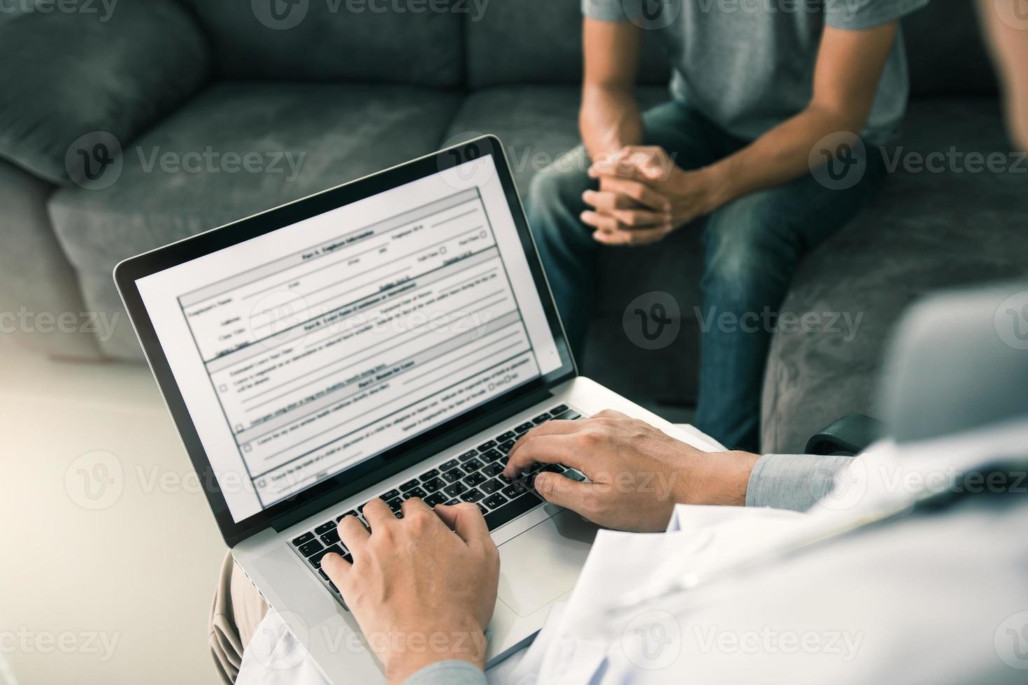 Doctor is using a laptop while typing the patient personal history record and giving advice about the patient home treatment. photo