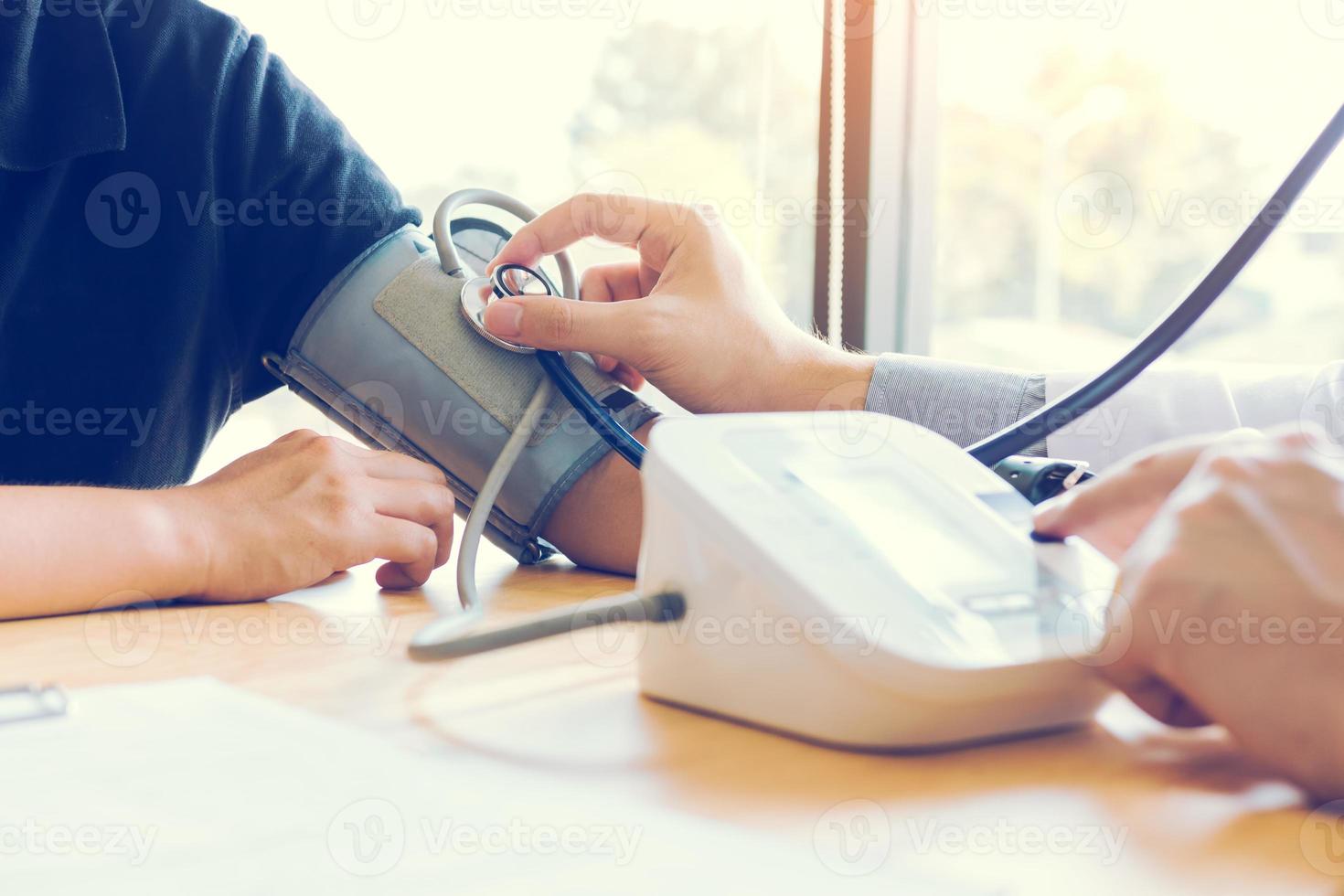 Asian doctor female measuring blood pressure of male patient at clinic office room. photo
