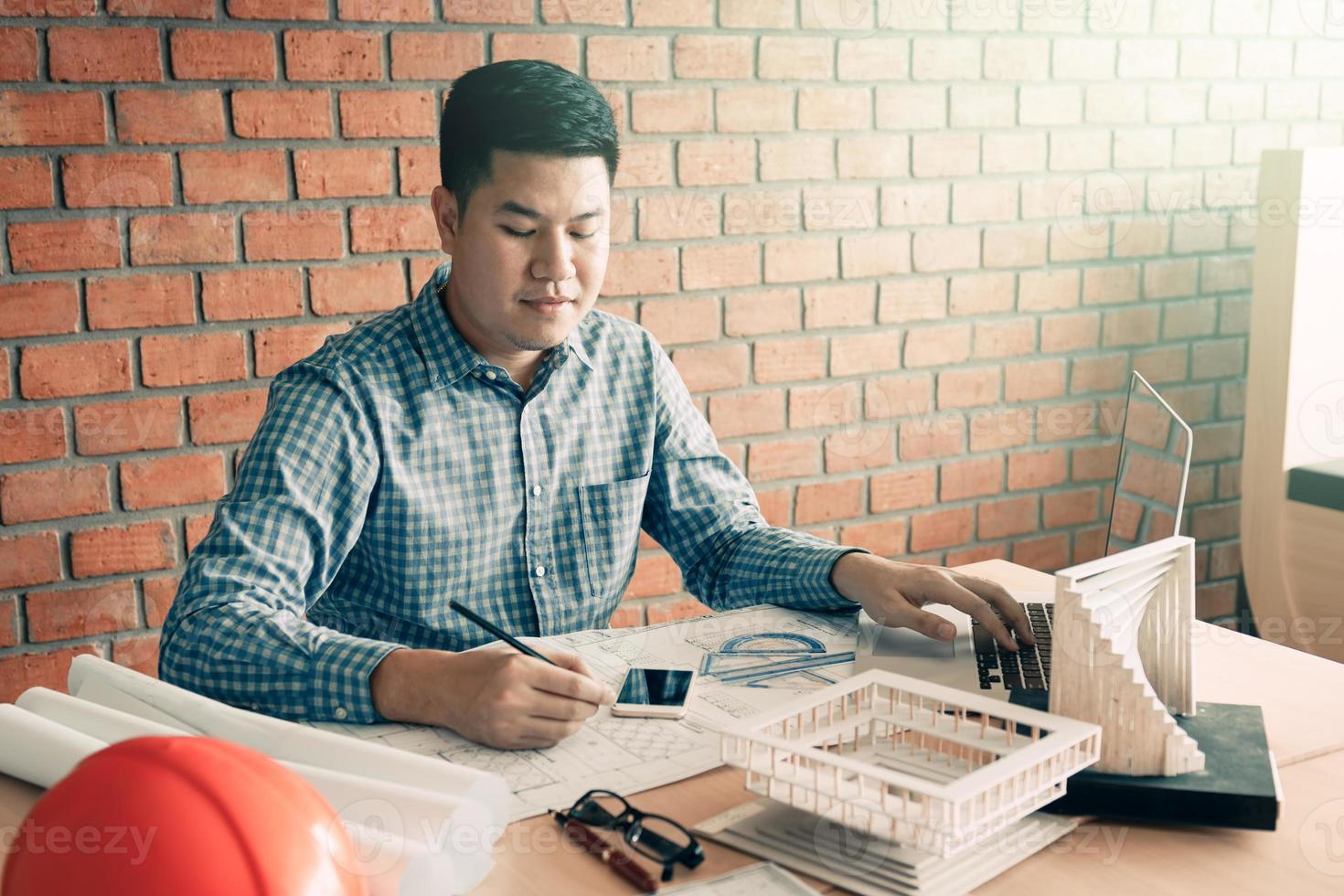 Architect asian man working in his office with sitting and typing on laptop. photo